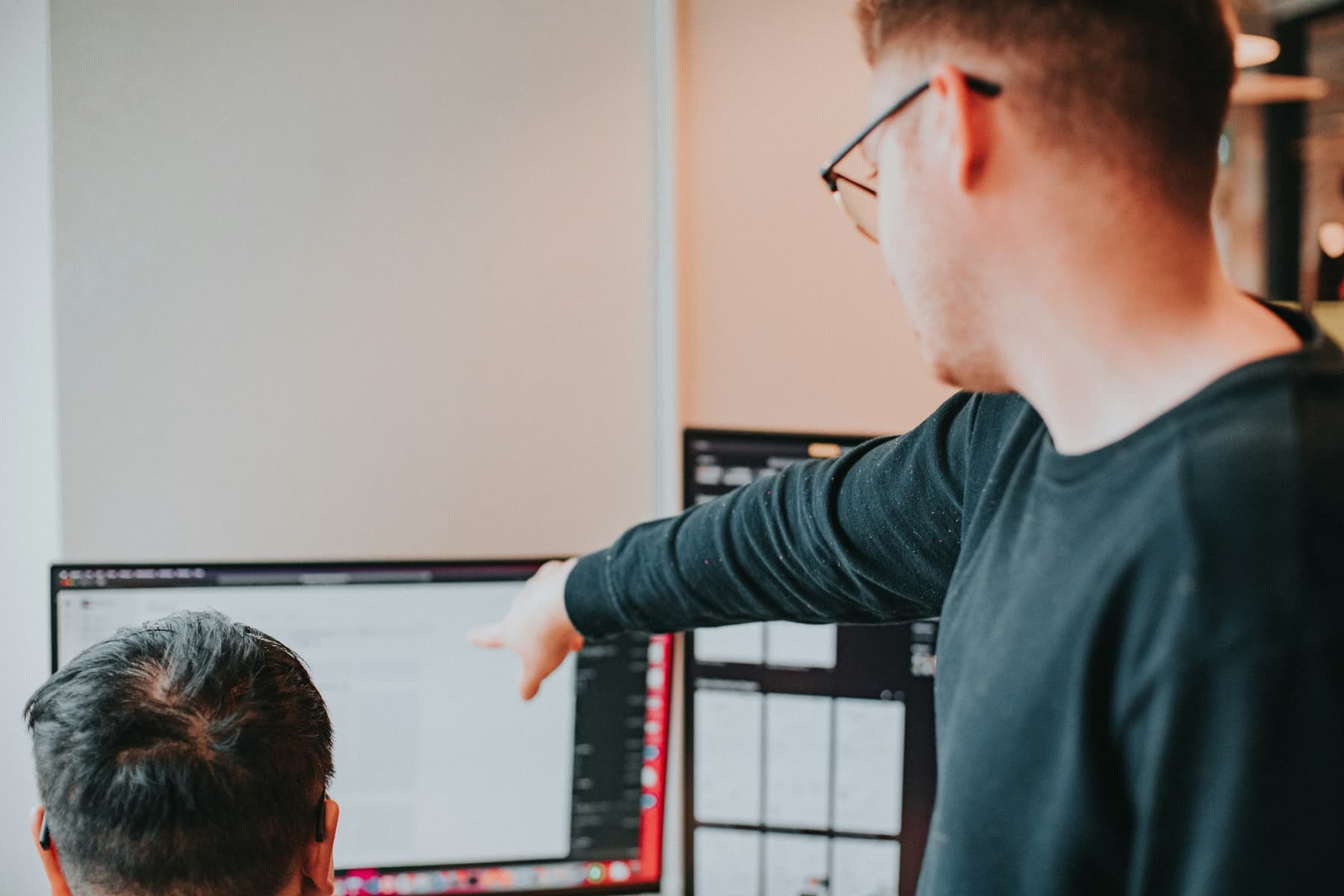 Two team members reviewing a page design on a large monitor